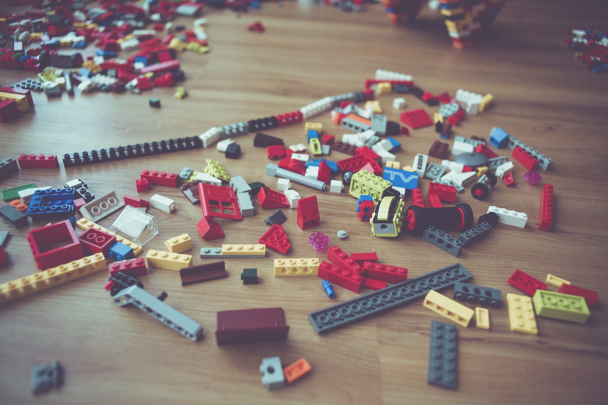 Hög med spridda, färgglada Lego-klossar på ett trägolv
